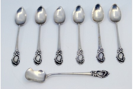 Conjunto de seis colheres de café e pá de açúcar em prata com relevos envolvendo cartelas para monogramas nos cabos.